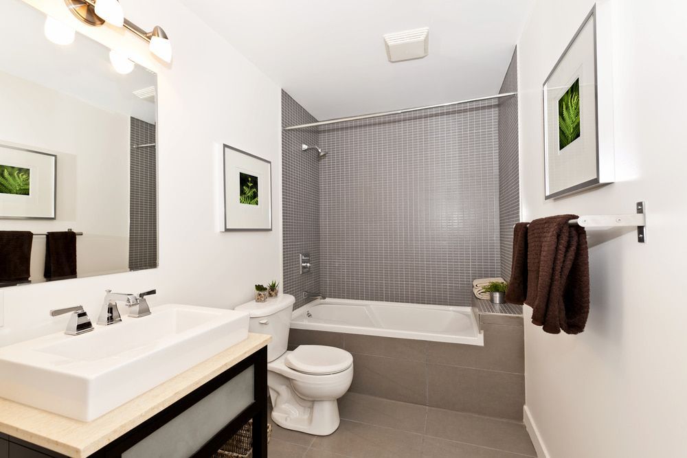 A Bathroom With A Sink, Toilet, Tub And Mirror — DMK Plumbing in Kempsey, NSW