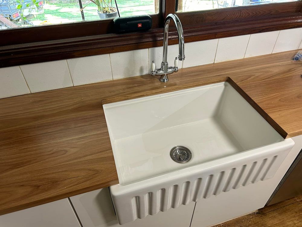A Kitchen Sink With A Wooden Countertop And A Faucet — DMK Plumbing in Crescent Head, NSW