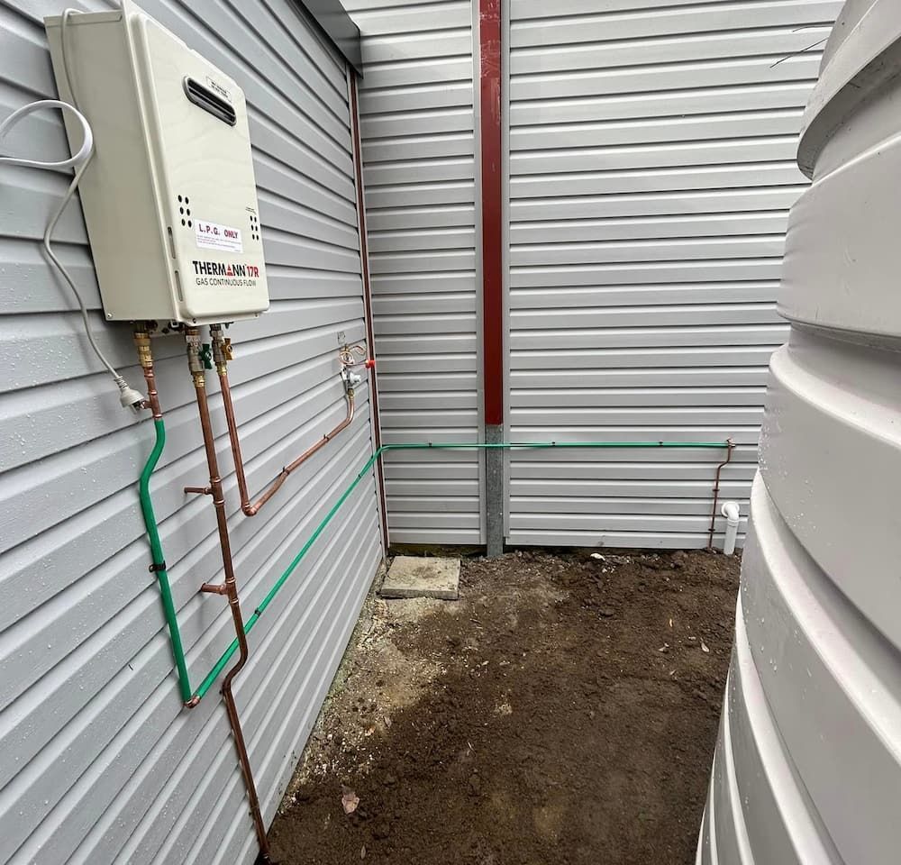 A Water Heater Is Installed On The Side Of A Building — DMK Plumbing in Crescent Head, NSW