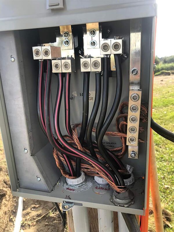 Electrical service box with black and red wires connected to terminals and ground bar.