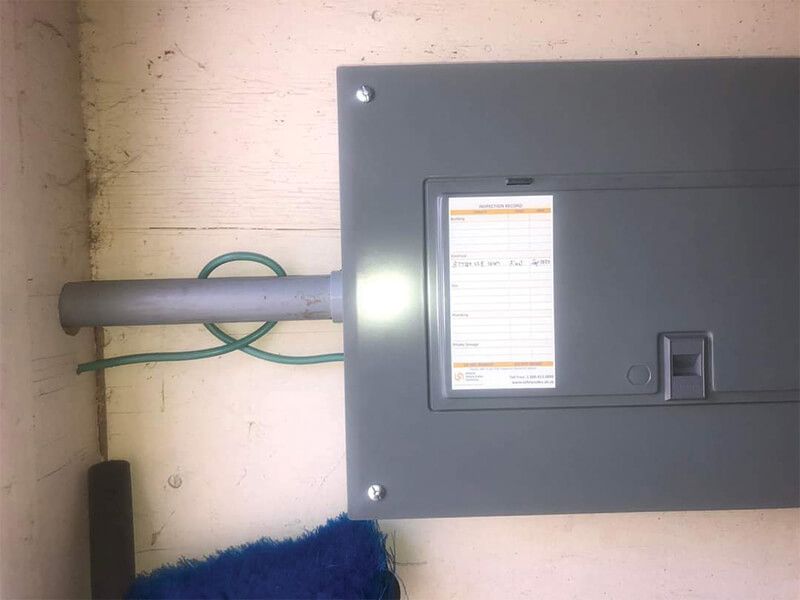 Electrical panel mounted on a wall; metal conduit and green grounding wire attached.