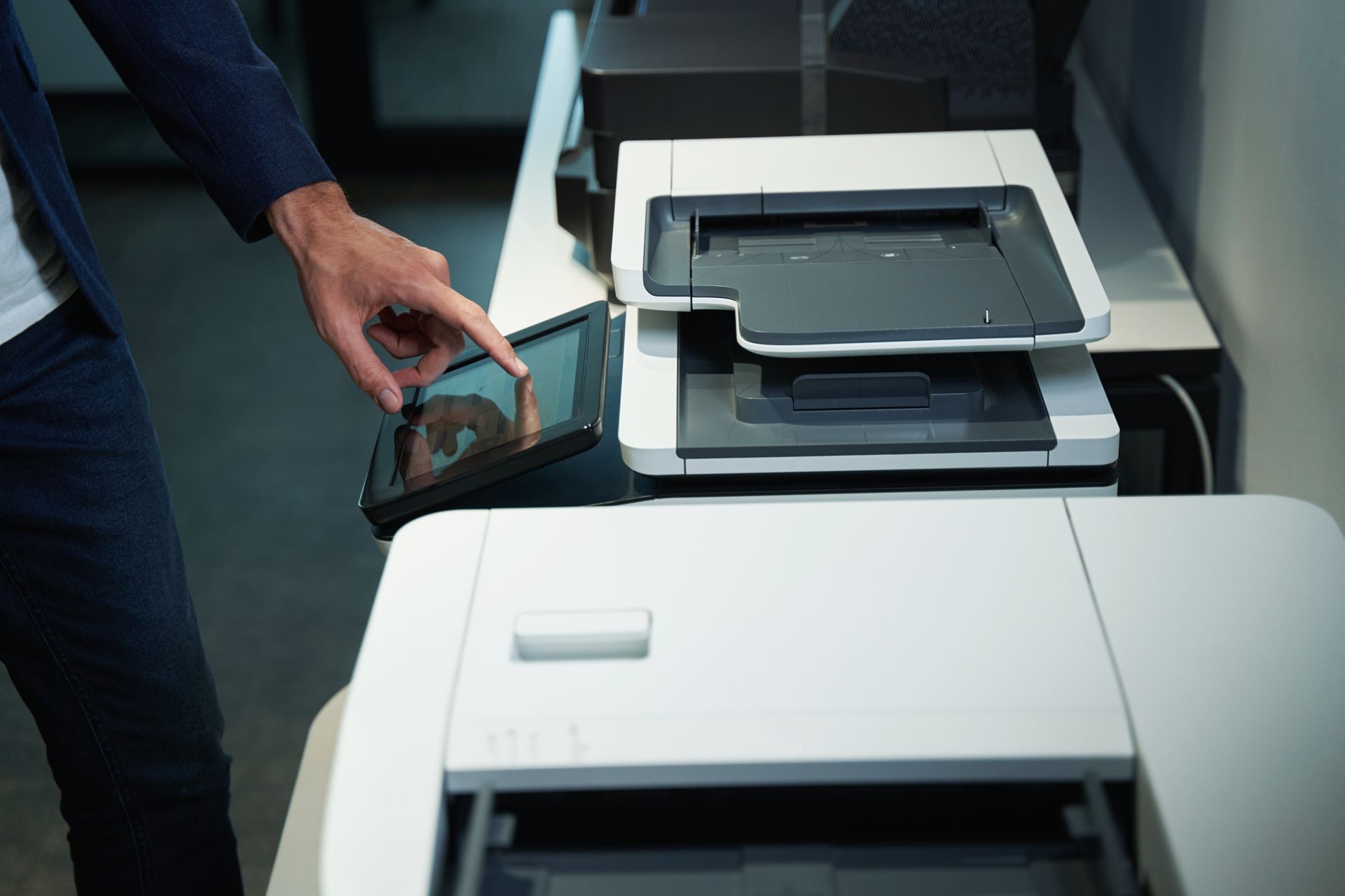 A man is using a tablet in front of a printer.