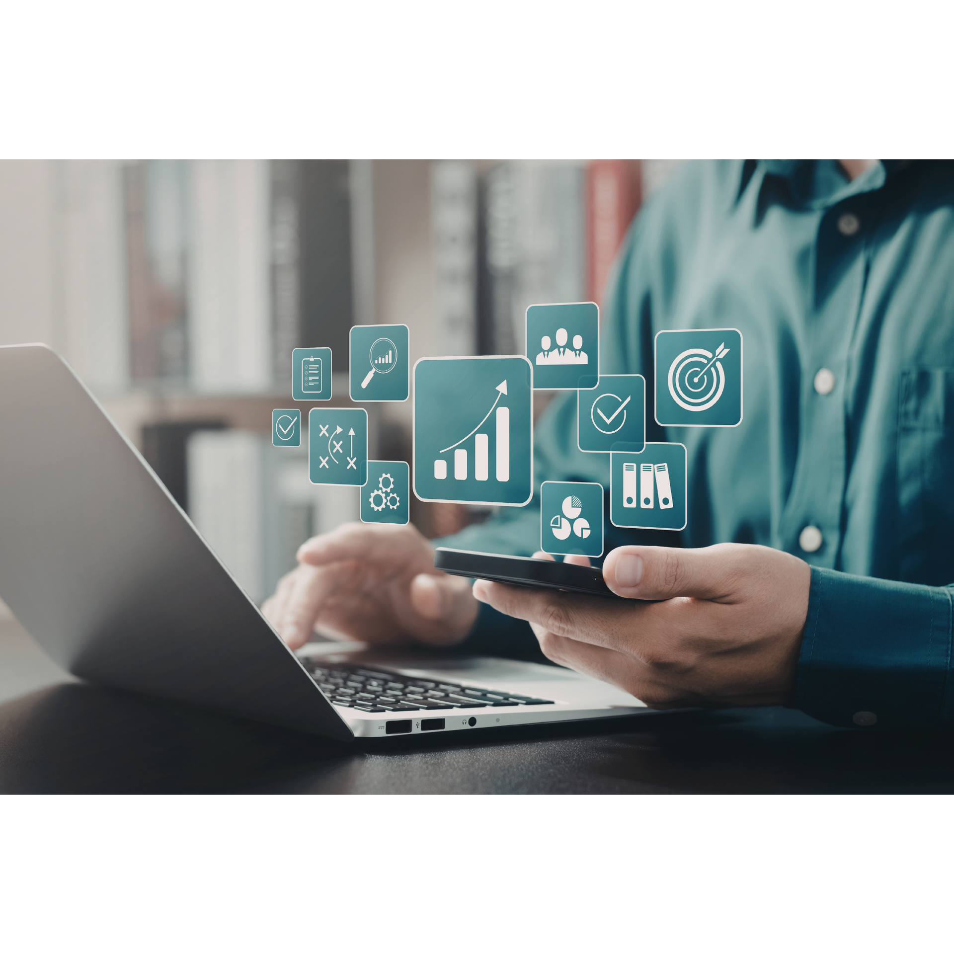Person using a smartphone beside a laptop, with floating business analytics icons in a modern office setting