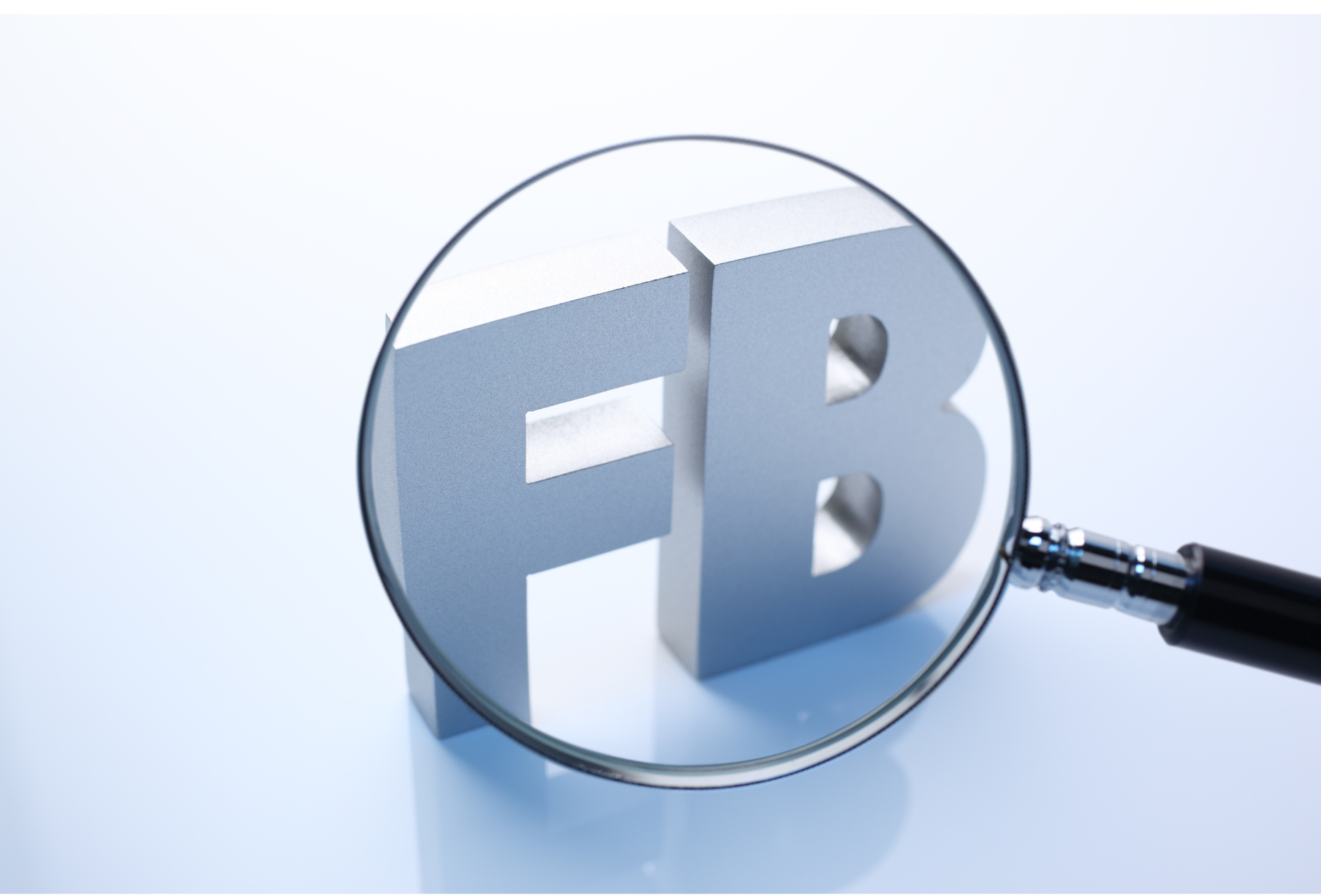 Facebook logo viewed through a magnifying glass on a light blue background
