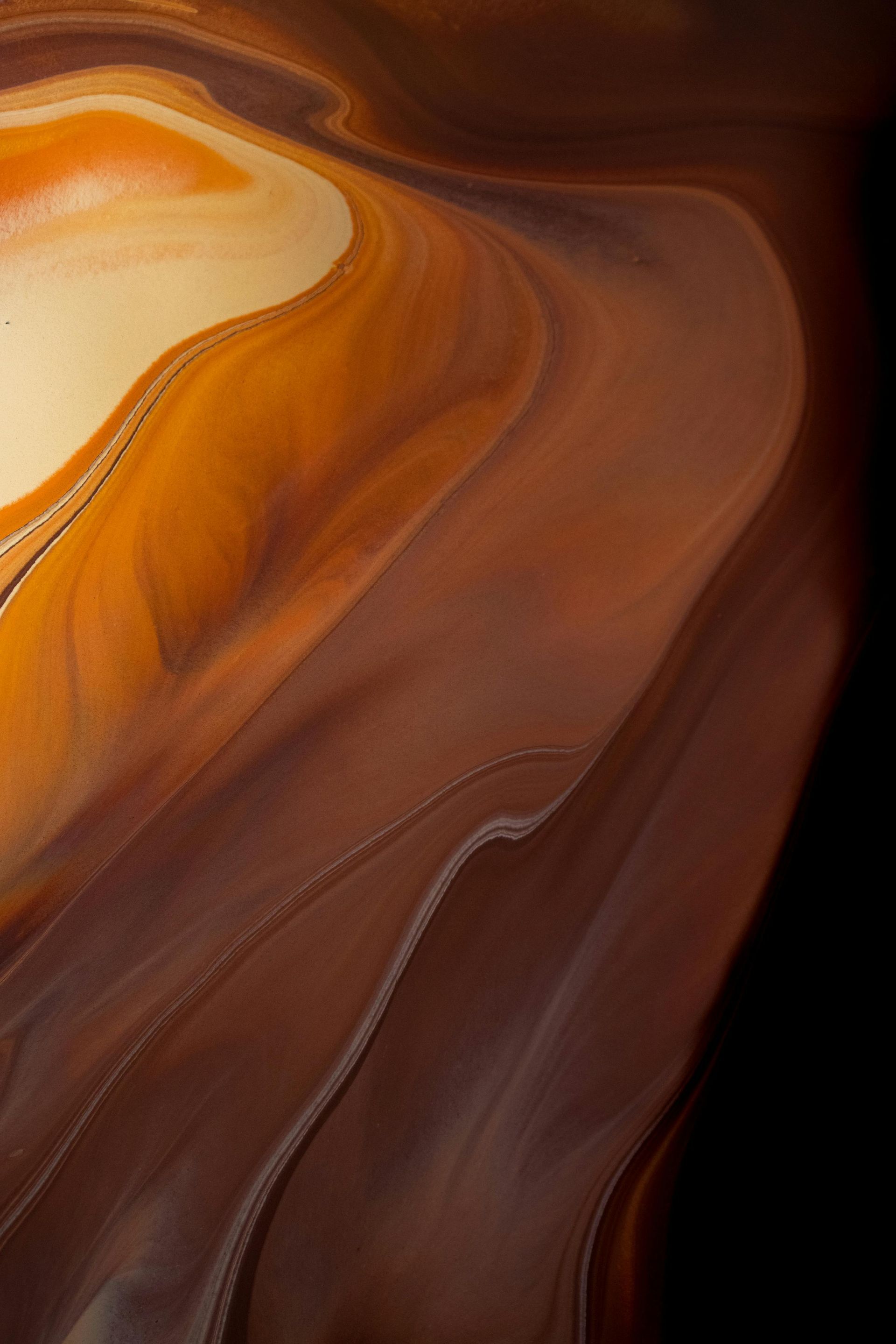 A close up of a brown and orange swirl on a black background.