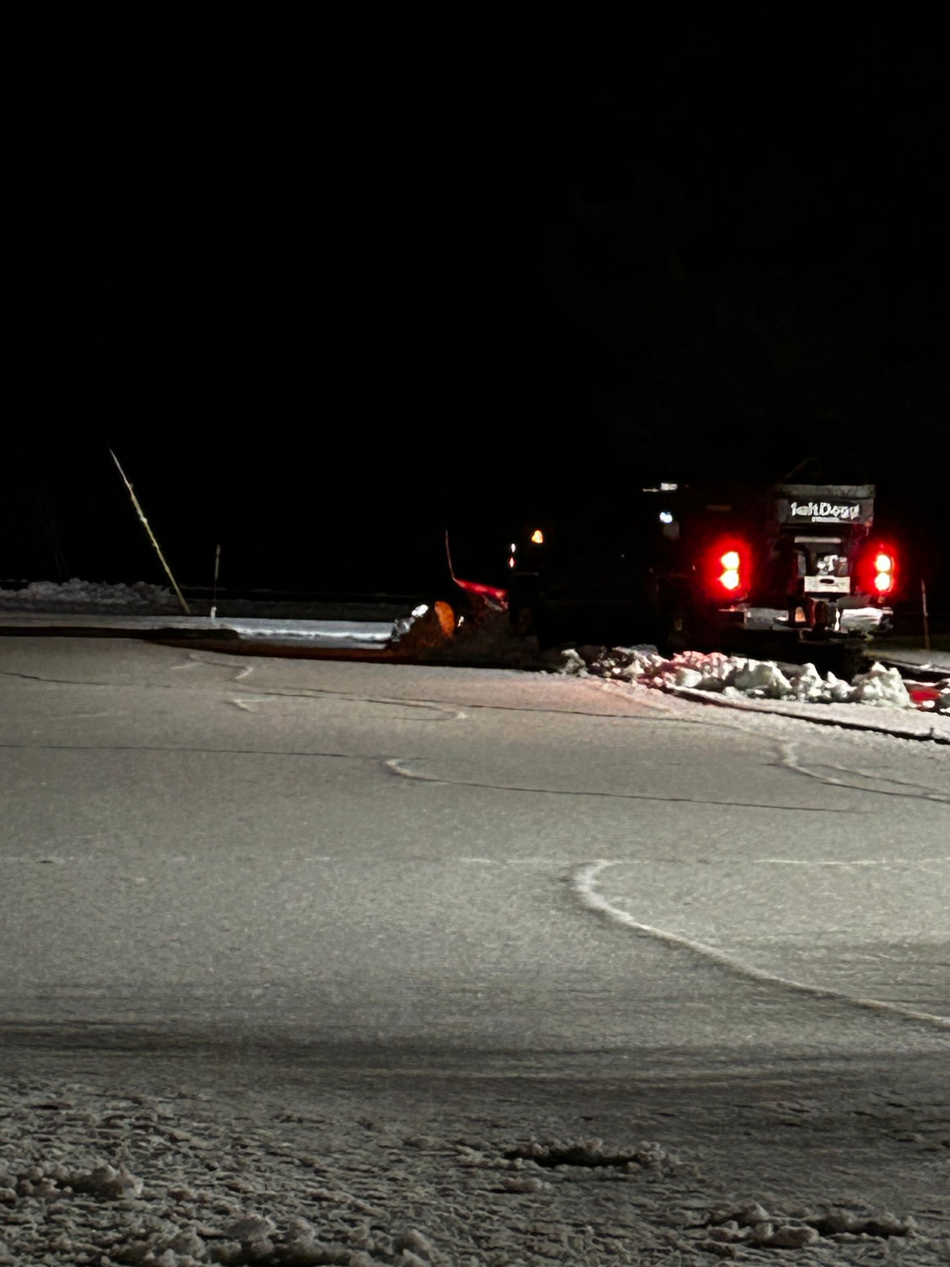 A truck is driving down a snowy road at night