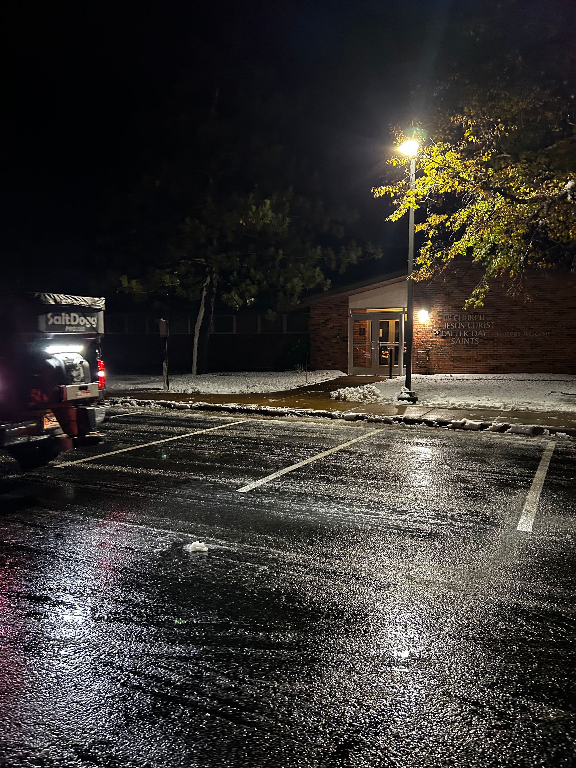 A parking lot with a building in the background at night.