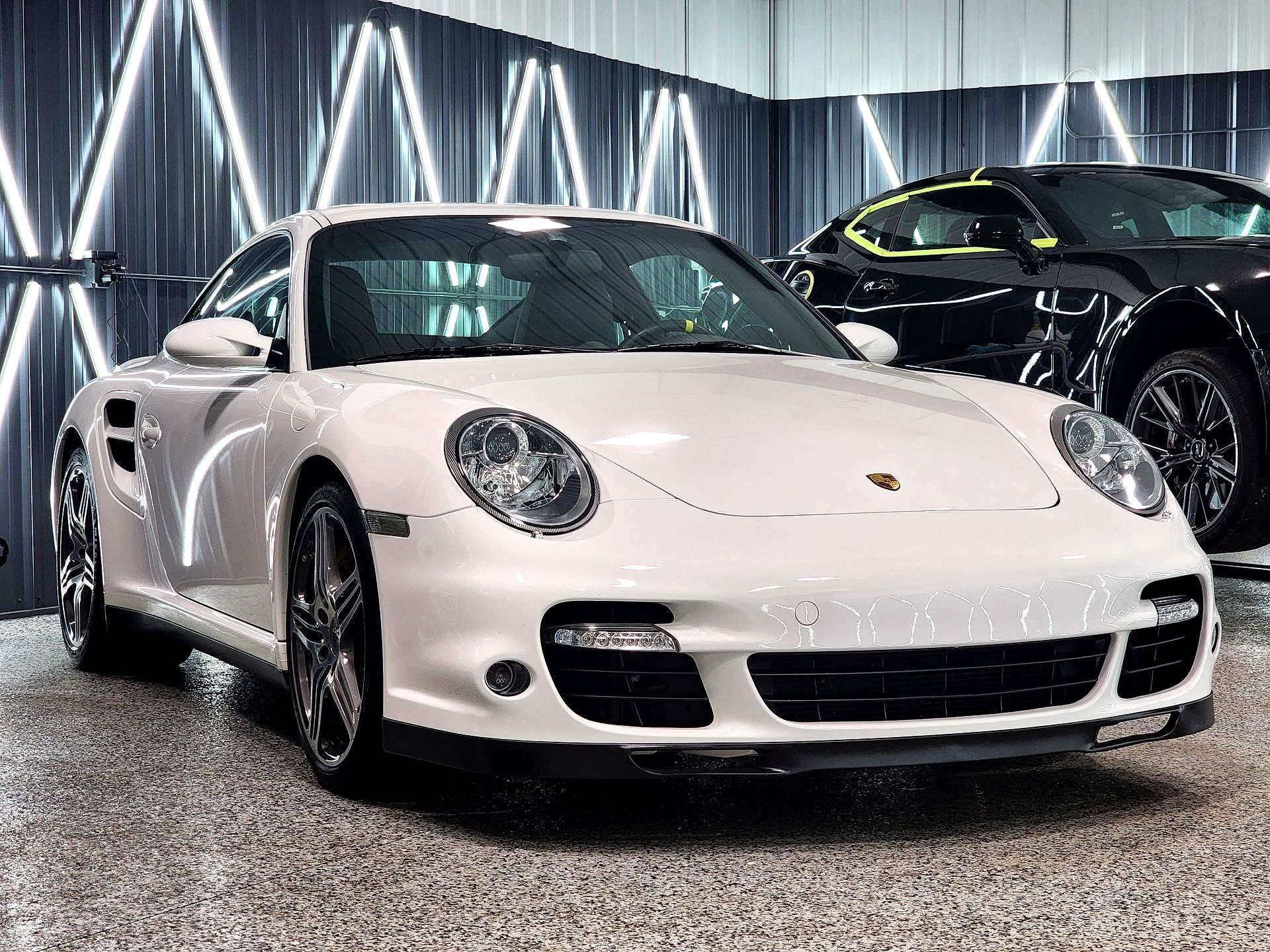 A white porsche 911 turbo is parked in a garage.