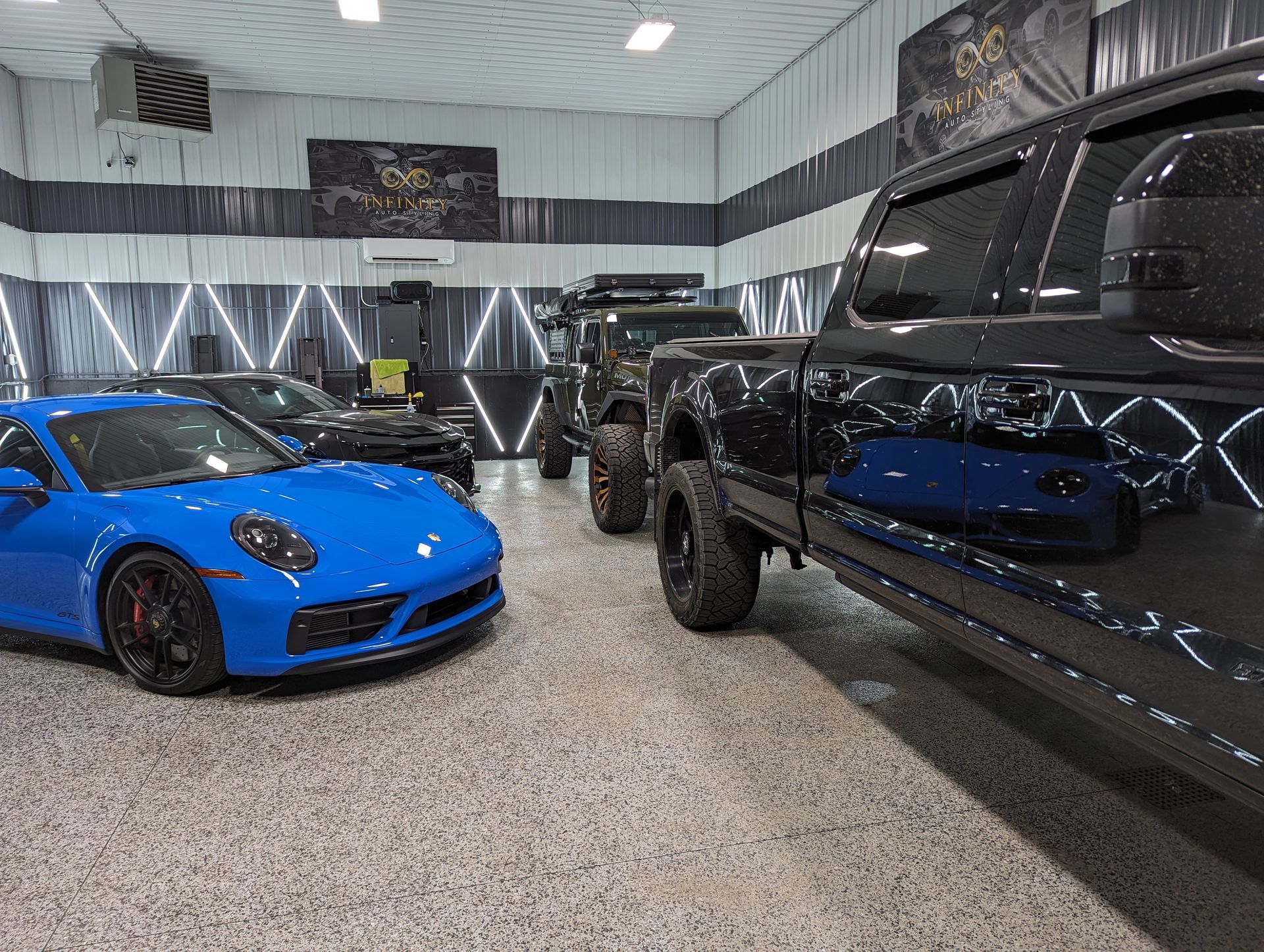 A blue sports car and a black truck are parked in a garage.