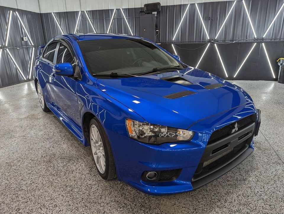 A blue mitsubishi lancer is parked in a garage.