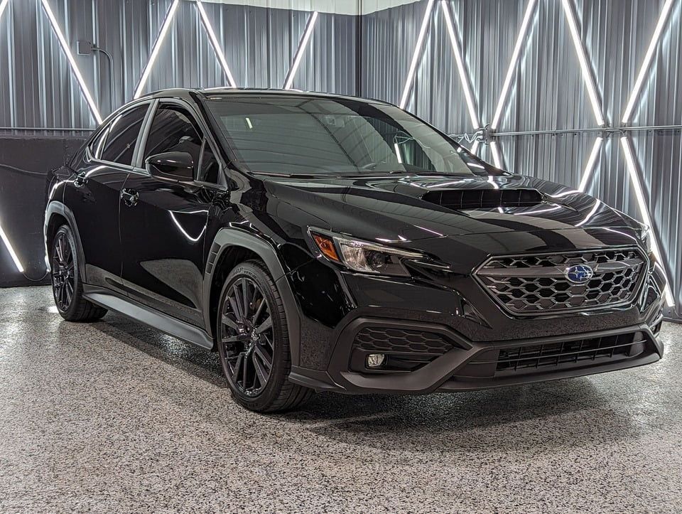 A black subaru wrx sti is parked in a garage.