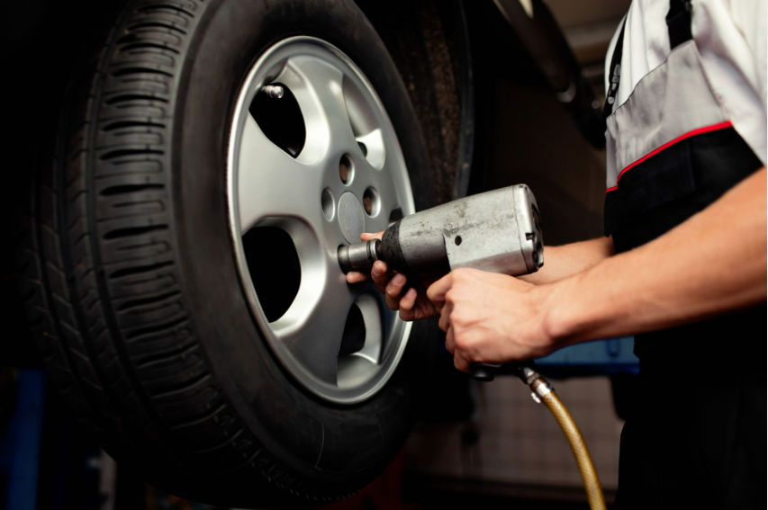 A man is changing a tire on a car with a wrench.
