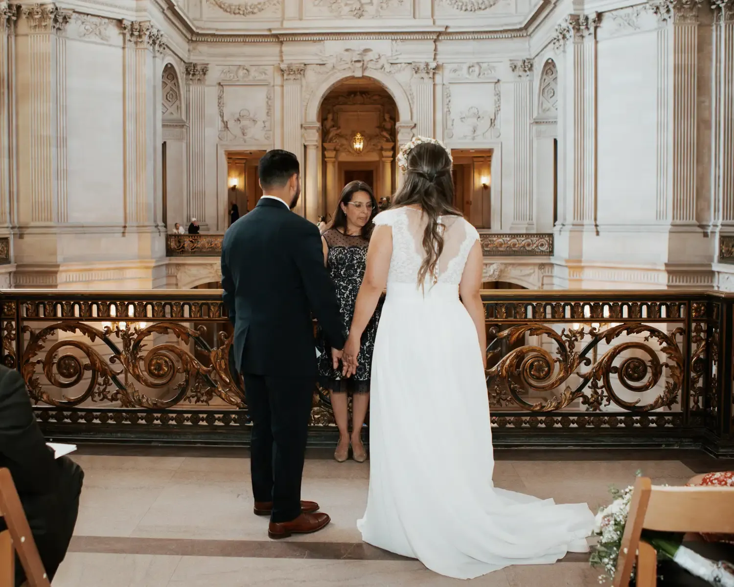 Couple holding hands during wedding ceremony in ornate hall, Bodas by Lina, Santa Clara, CA.