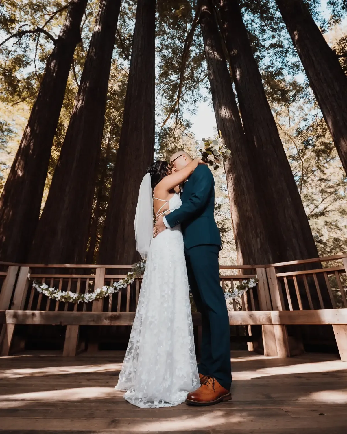 Bride and Groom kissing at a wedding ceremony under tall redwood trees. Bodas by Lina, Santa Clara, CA.