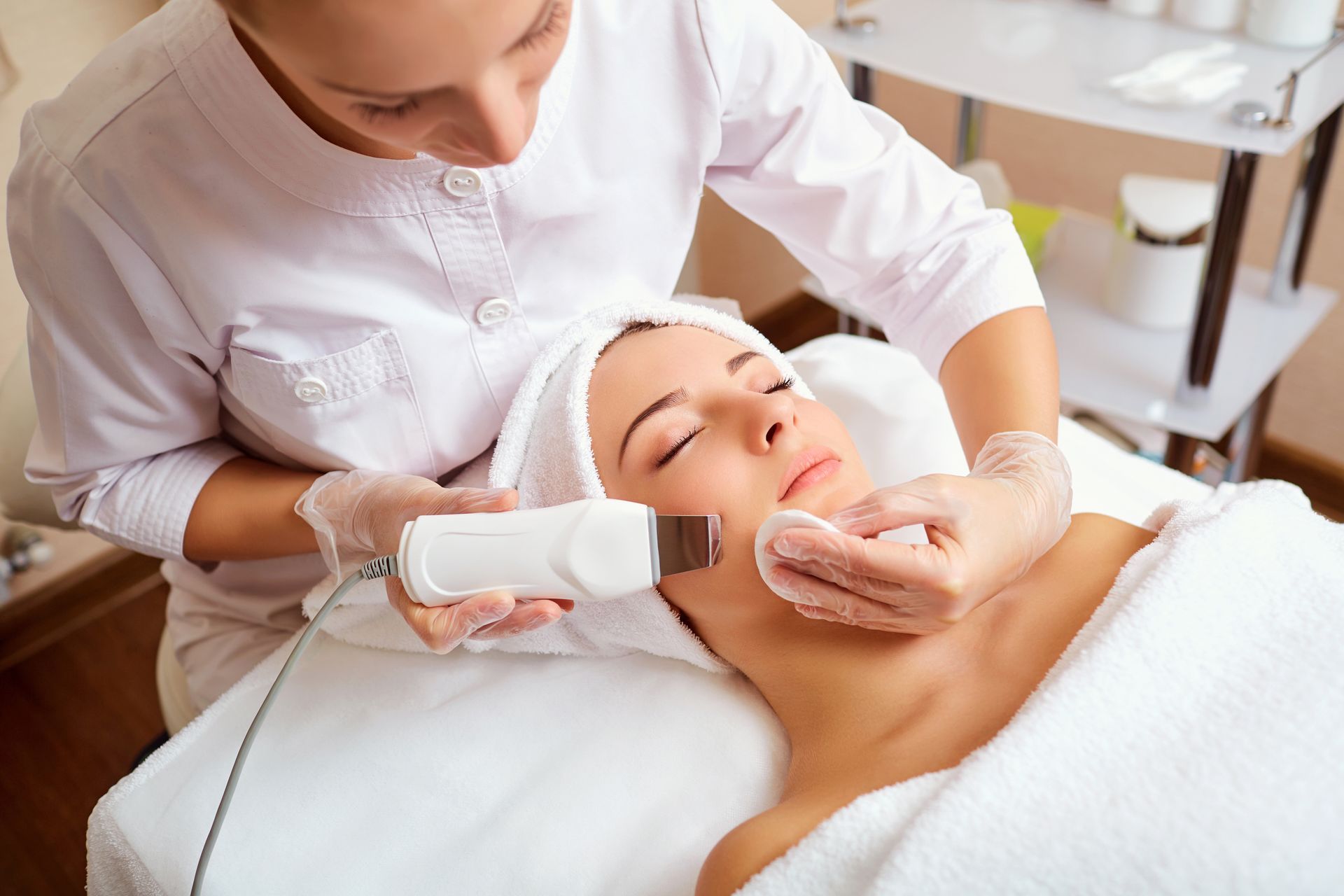 A spa professional using an ultrasonic device for deep facial cleansing treatment.