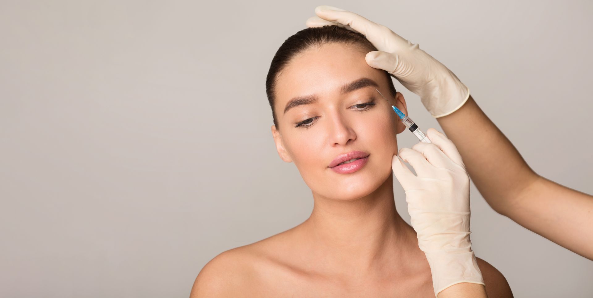 Healthcare professional administers an injection into a woman’s face.