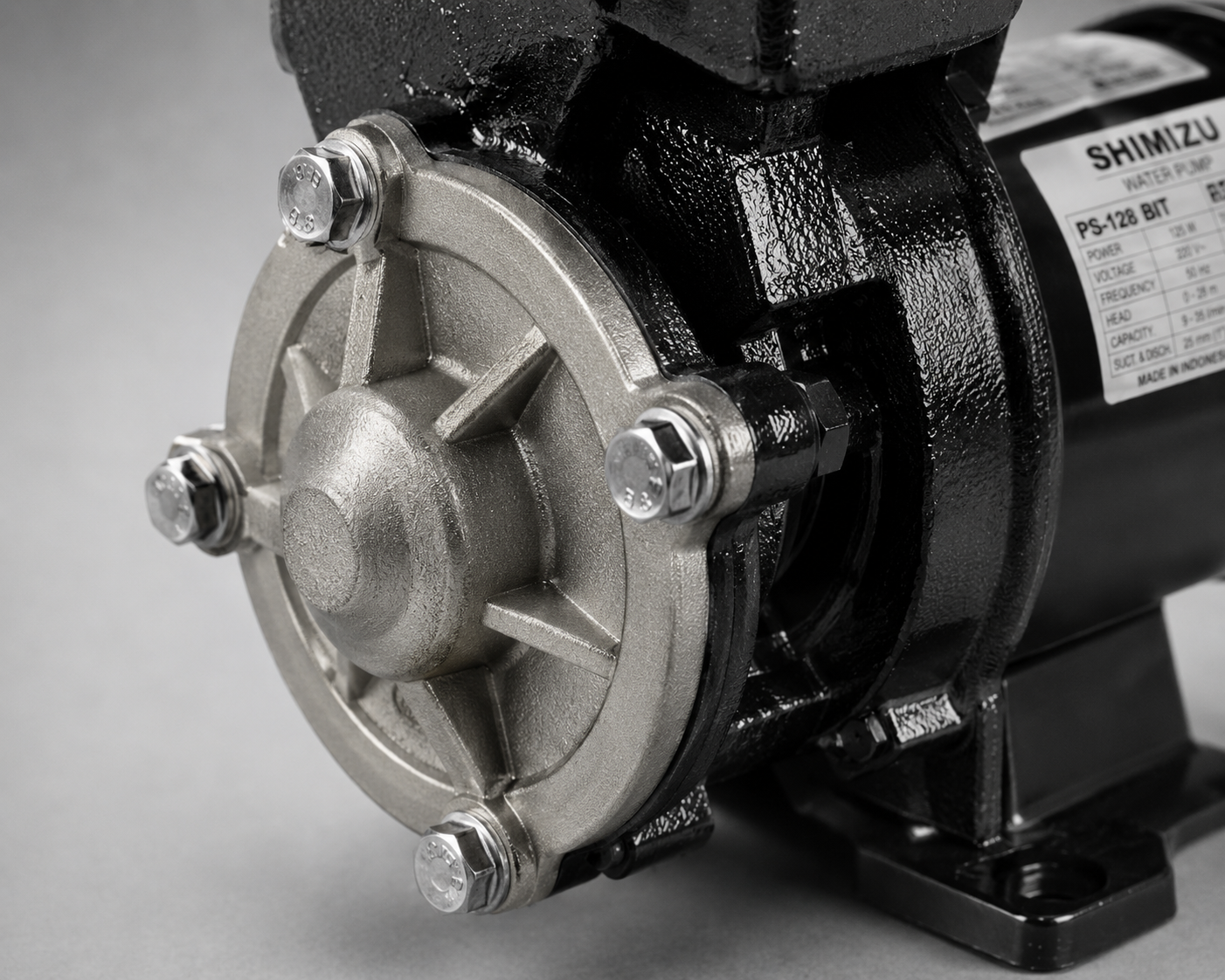 Close-up of a silver pump housing with bolts on a black motor base.