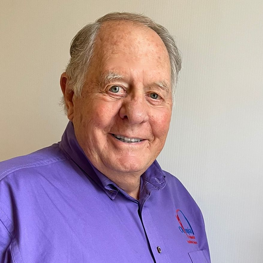 Smiling older man in a purple shirt; white background.