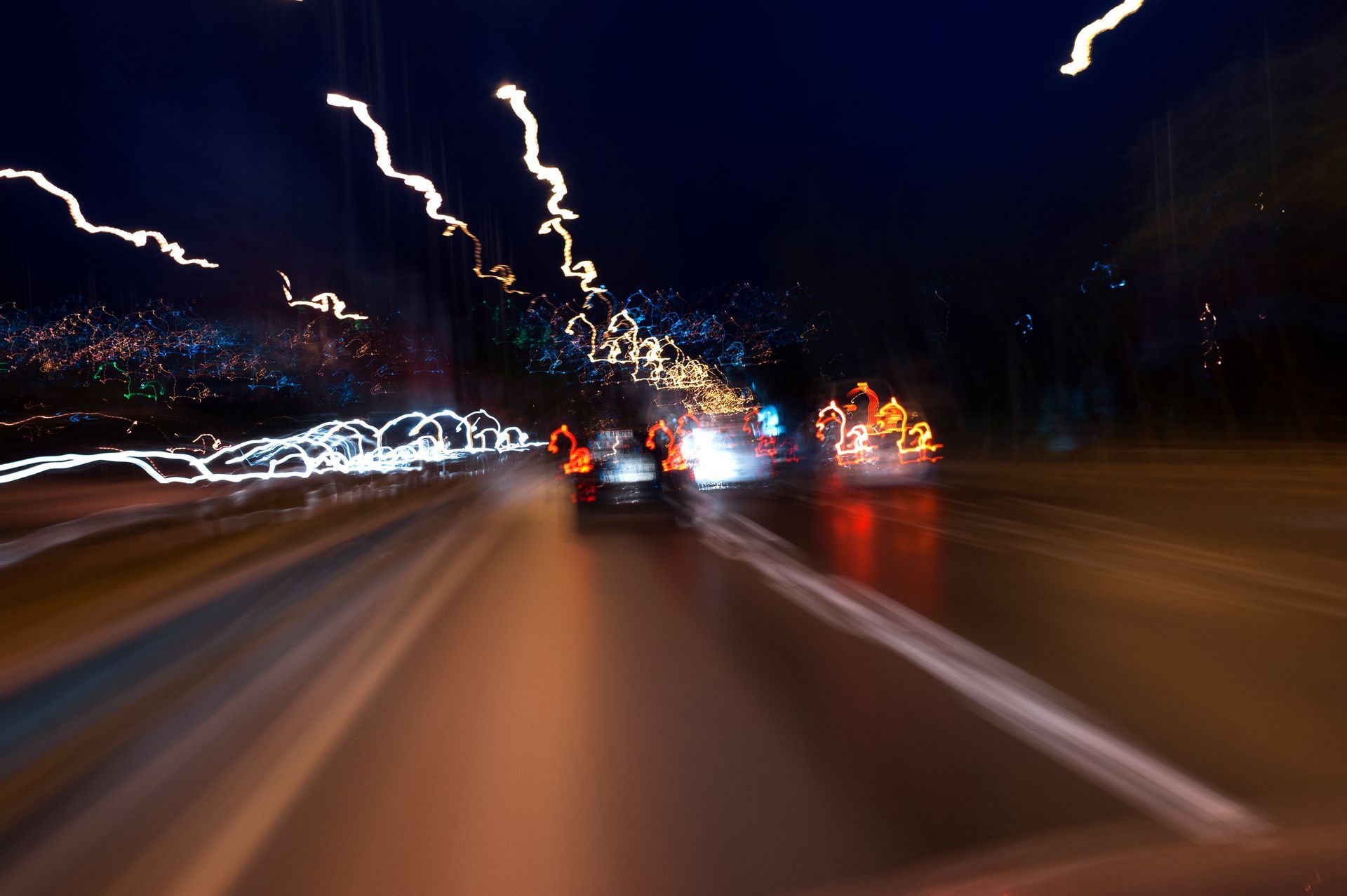 Nighttime road scene with blurred streaks of car lights.