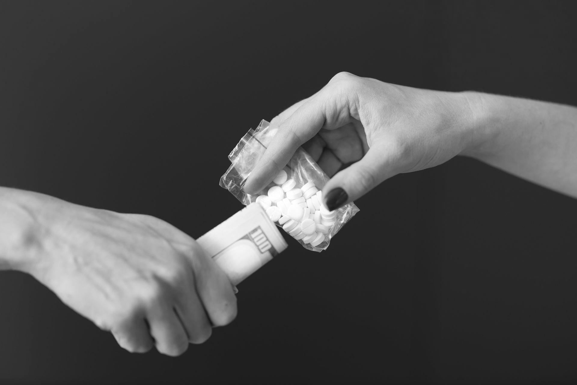 Hands exchanging money for pills in bags.