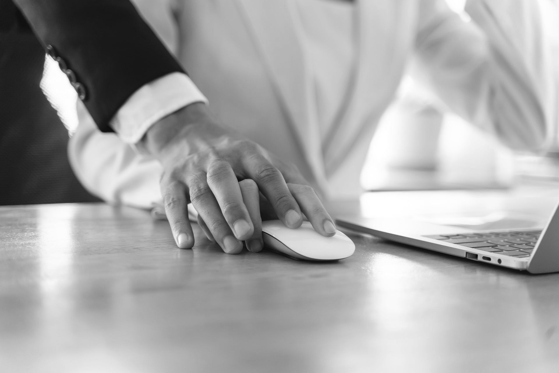 Man's hand on top of woman's hand using a computer mouse at a desk.