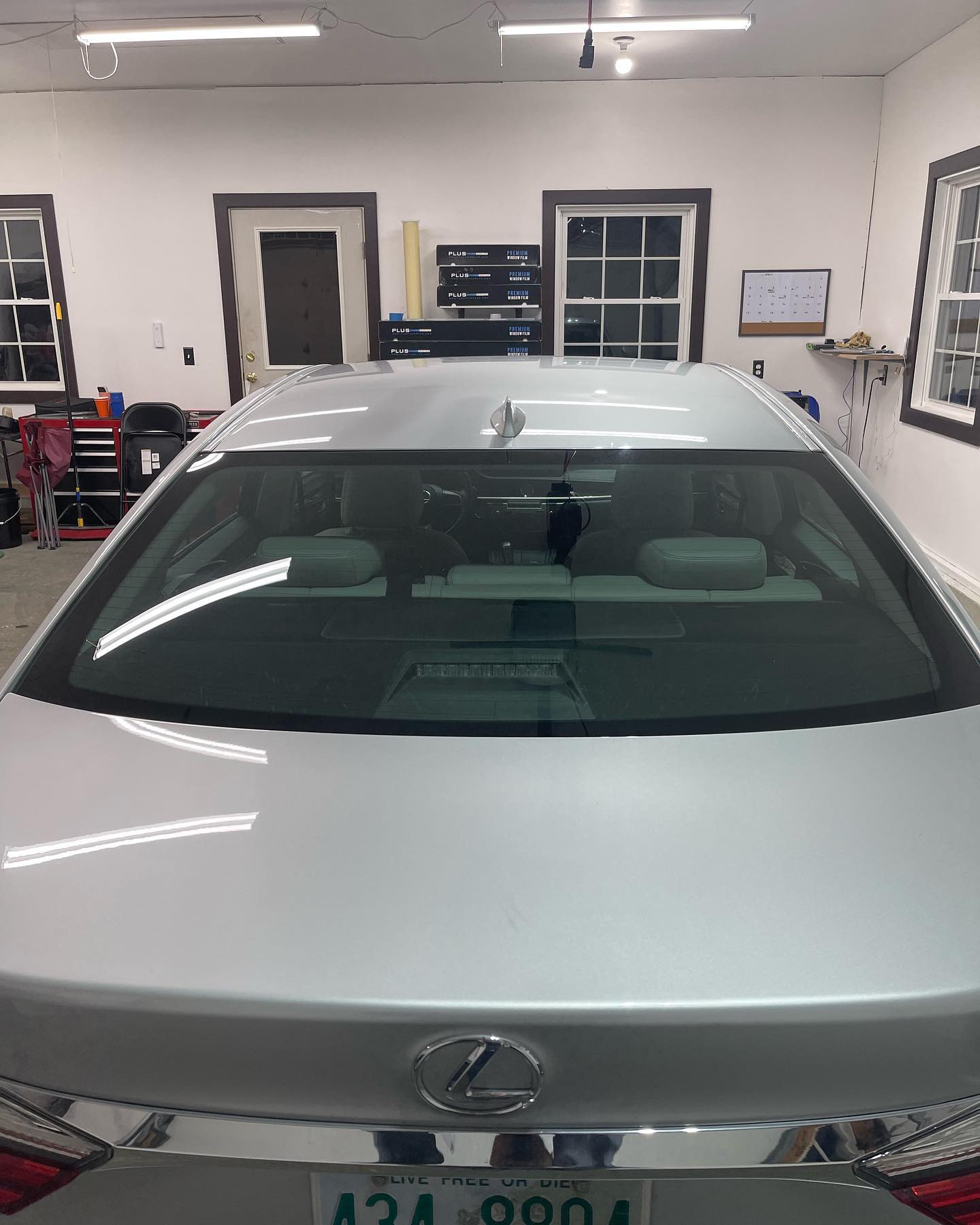 Silver car's rear, with a tinted back window and the garage behind it.