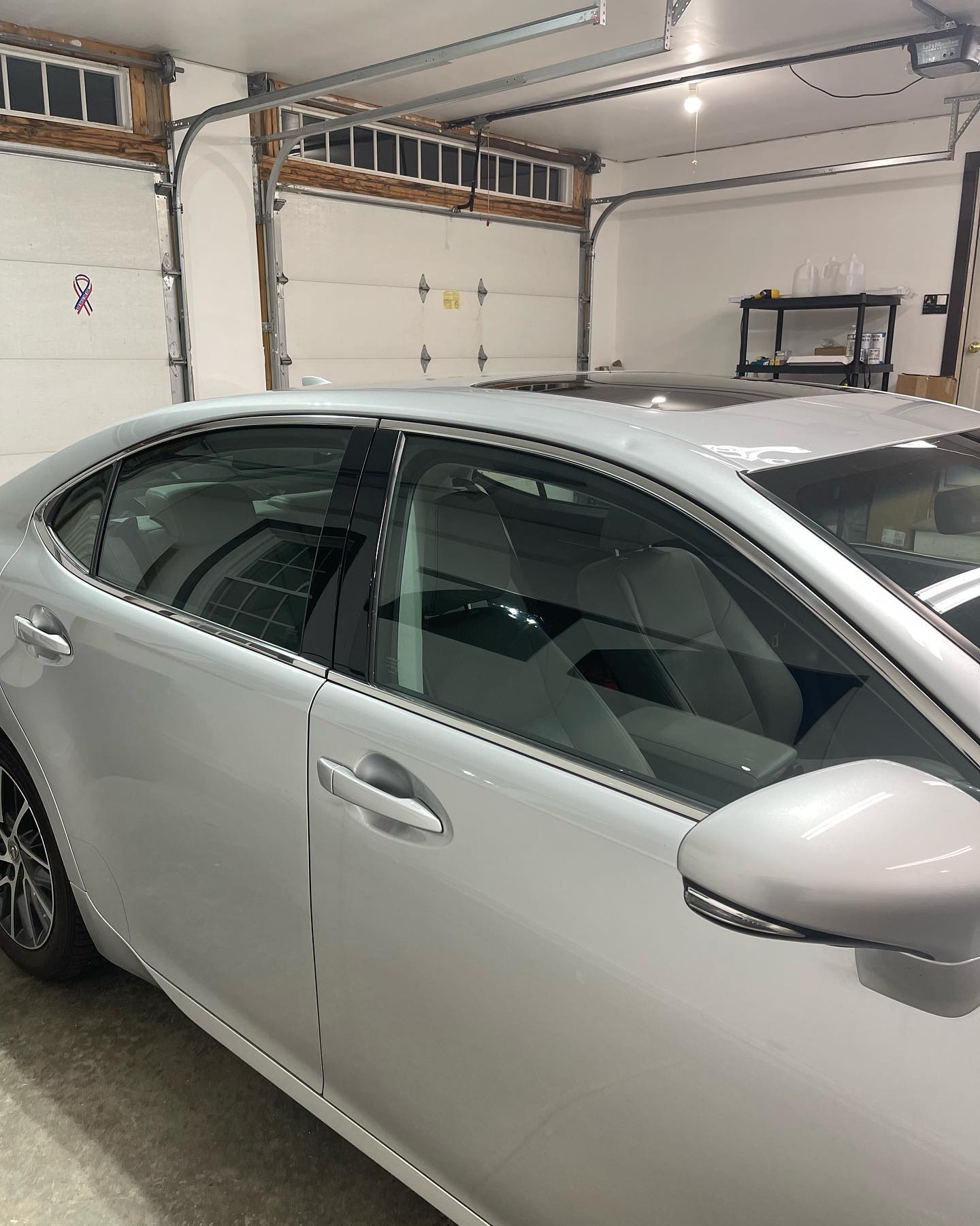 Silver car parked inside a garage; windows tinted, garage door partially open.