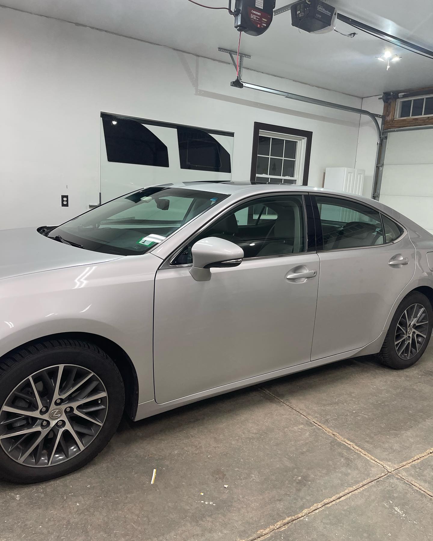 Silver sedan parked inside a garage; visible wheels, tinted windows.