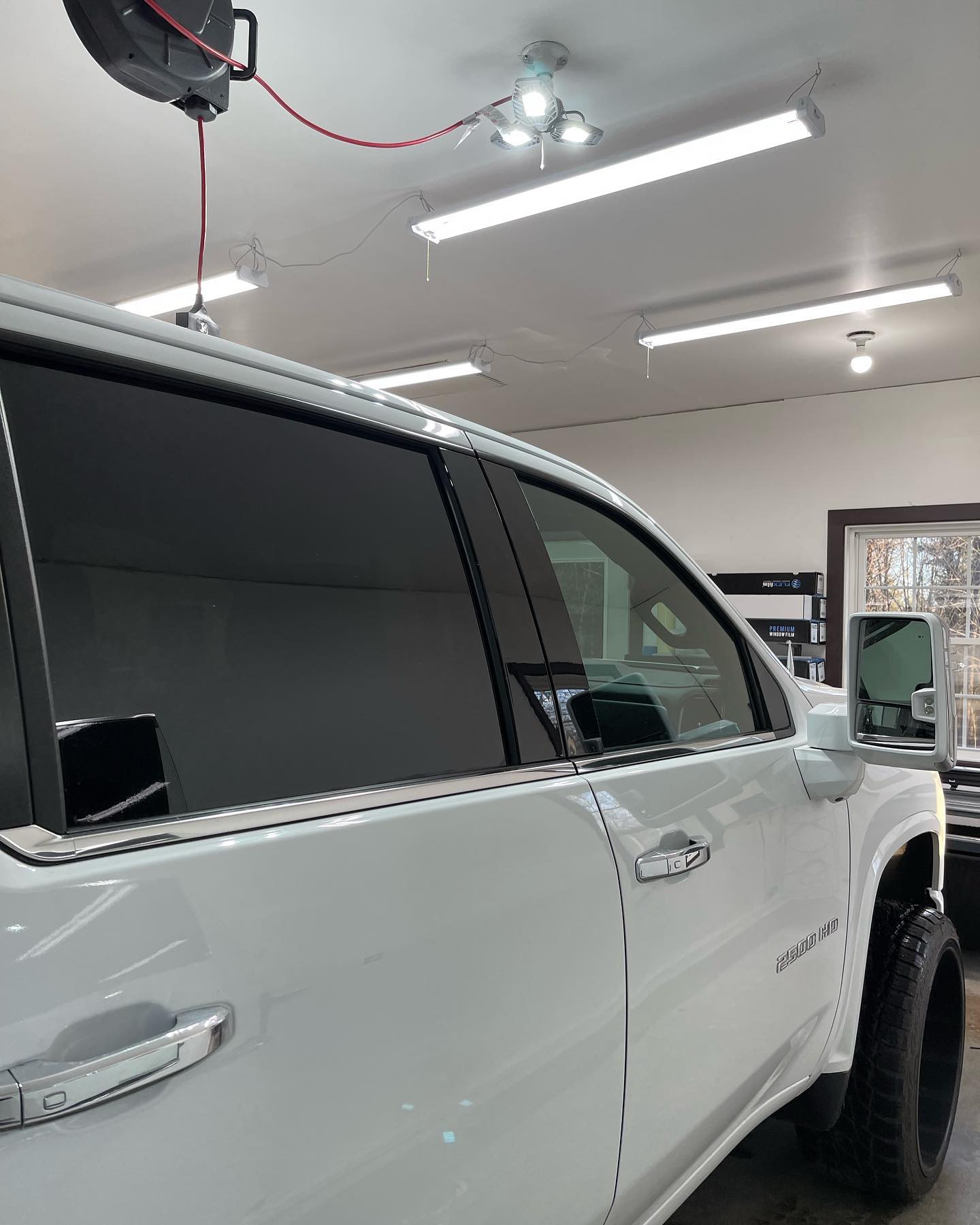 White truck with tinted windows inside a well-lit shop.