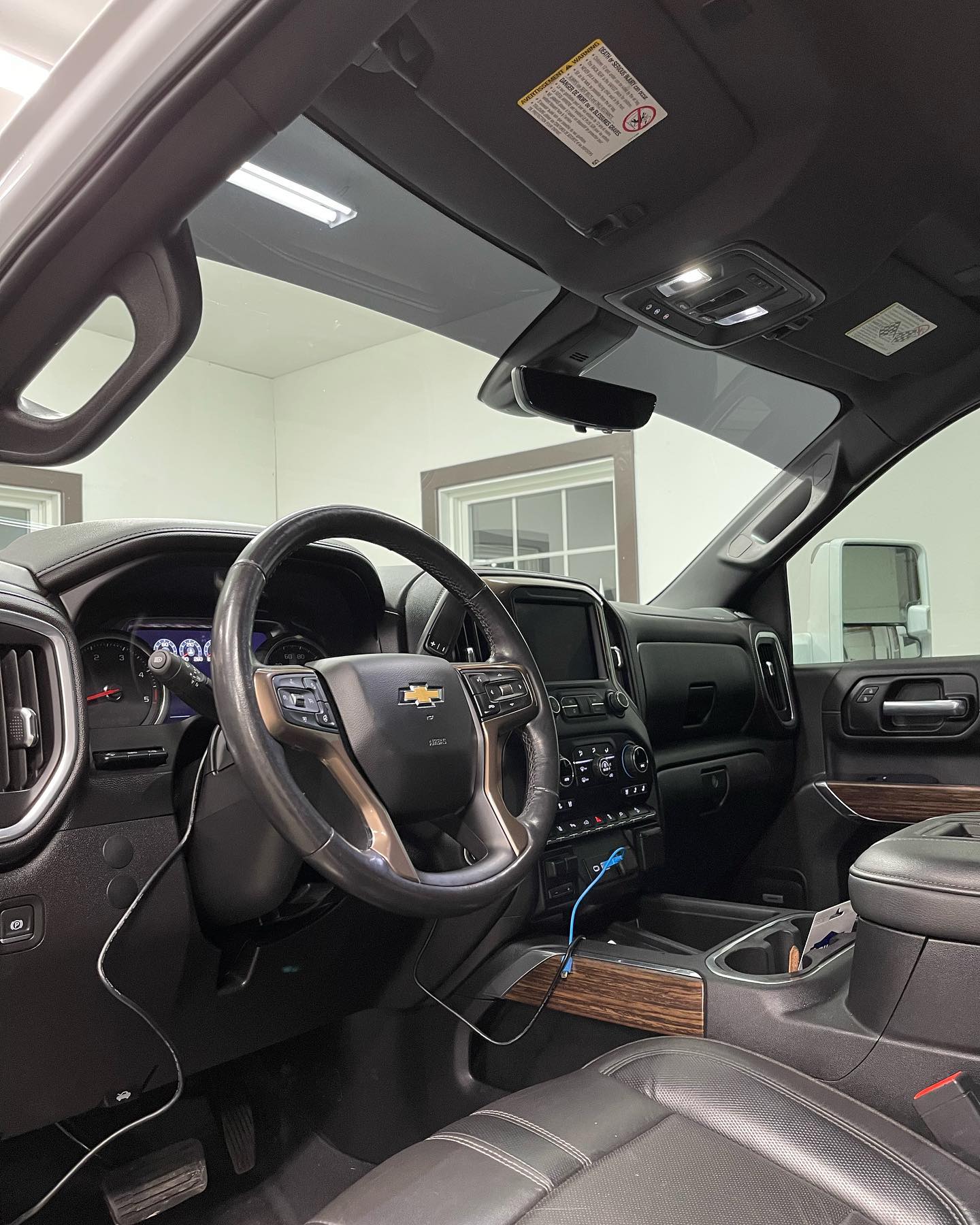 Interior view of a black Chevrolet truck with dashboard, steering wheel, and console visible.