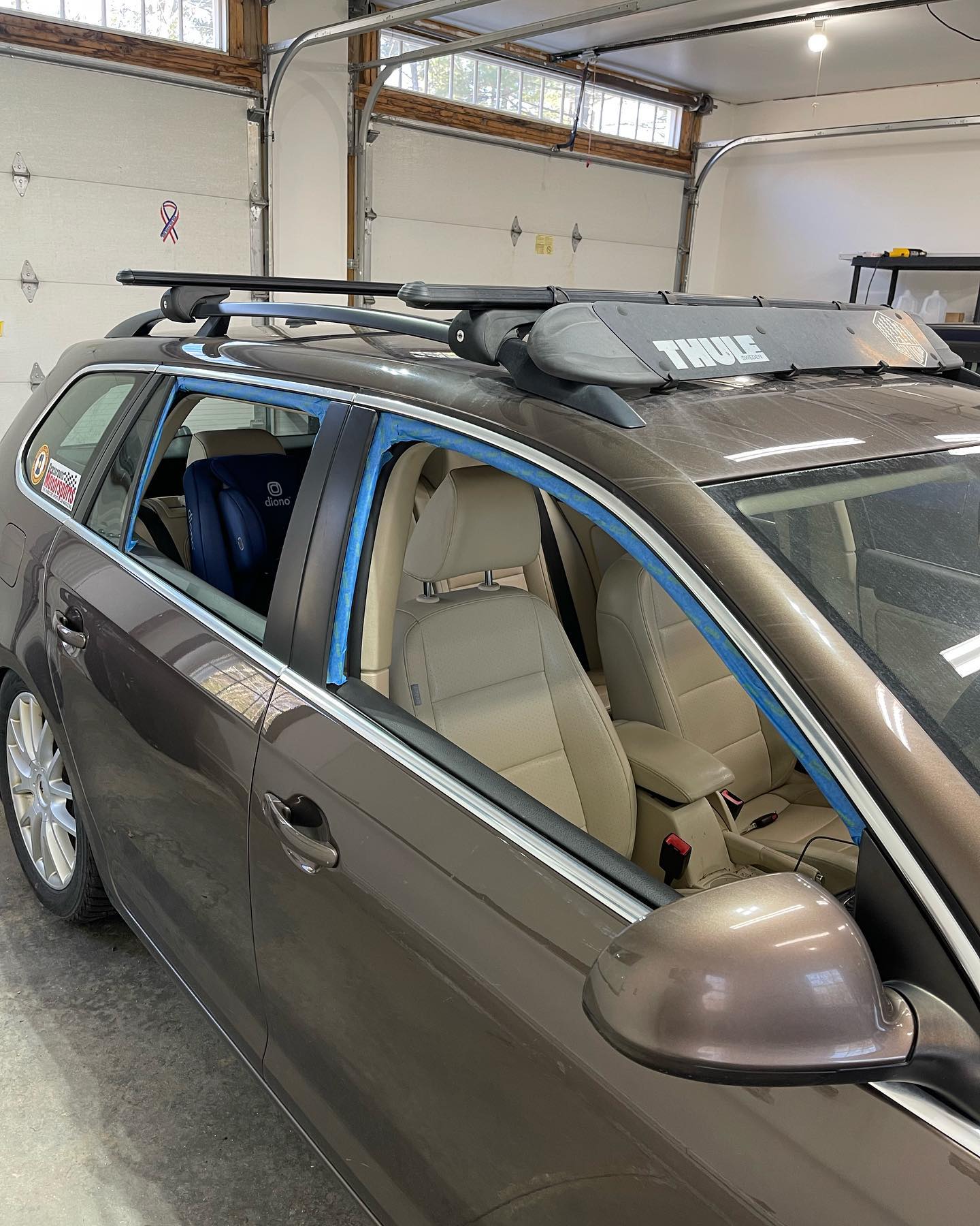 Brown station wagon with Thule roof rack inside a garage.