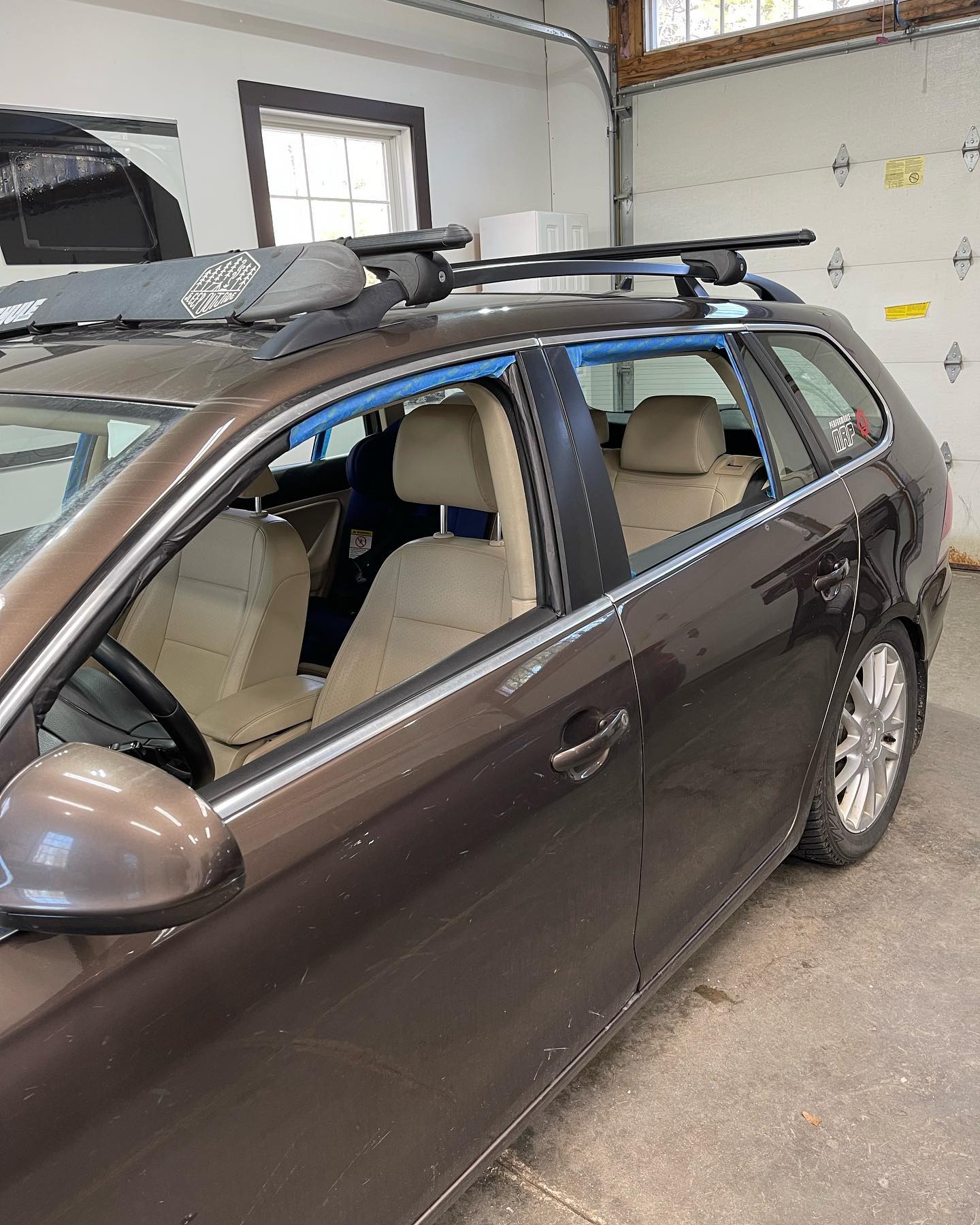 Brown station wagon with roof rack parked in a garage. Tan interior, silver wheels.