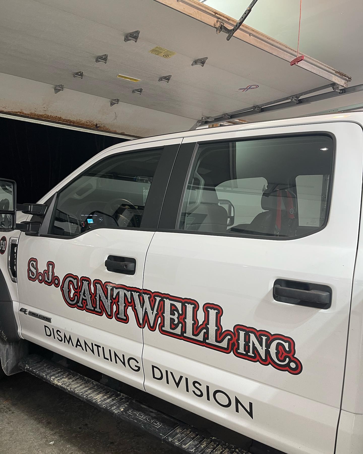 White S.J. Cantwell Inc. truck with red logo parked under a garage door. 