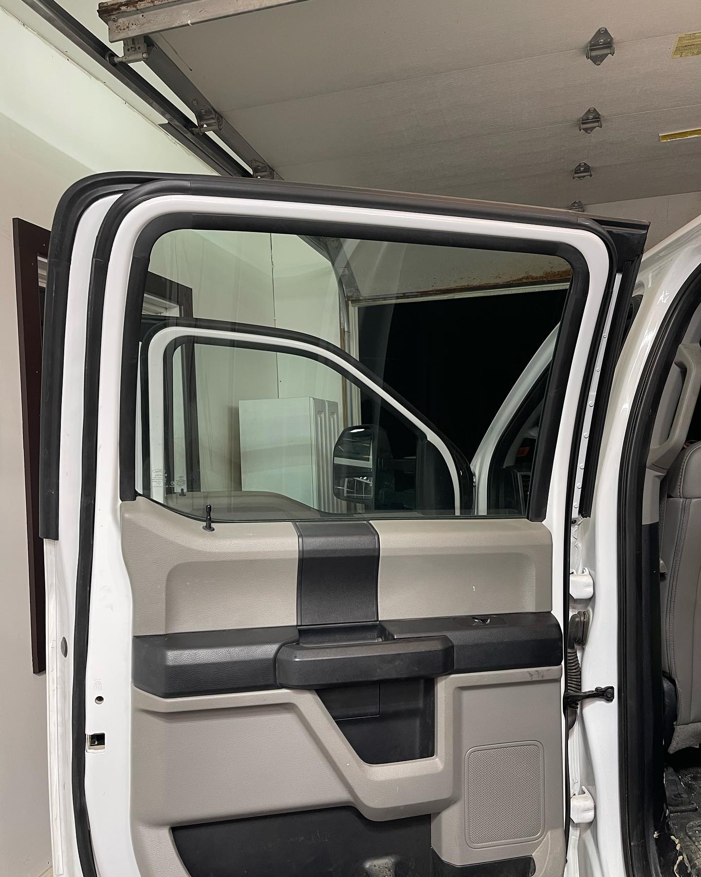 Open white truck door with black and gray interior; visible window frame.