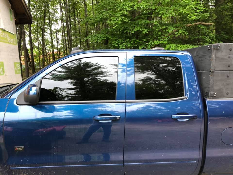 Blue pickup truck with dark tinted windows, parked outdoors near trees.