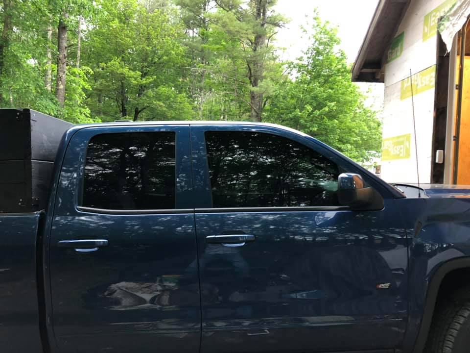 Blue pickup truck with tinted windows parked near a building and trees.