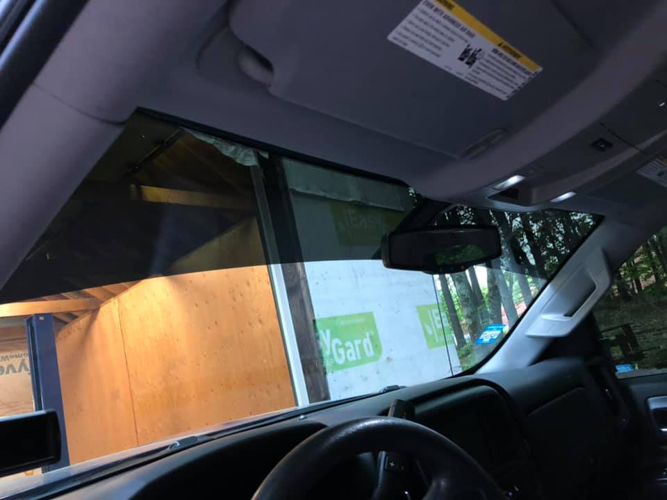 Interior view of a vehicle, windshield and dashboard visible. The sun visor is down, blocking the sun.