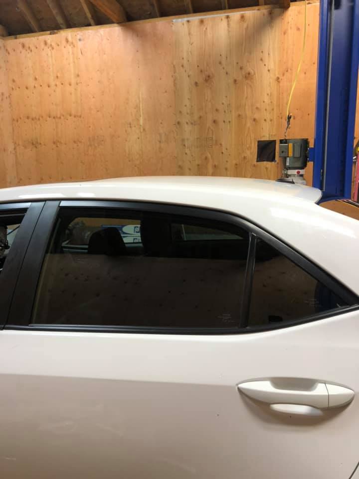 White car with tinted rear window, parked in a workshop.