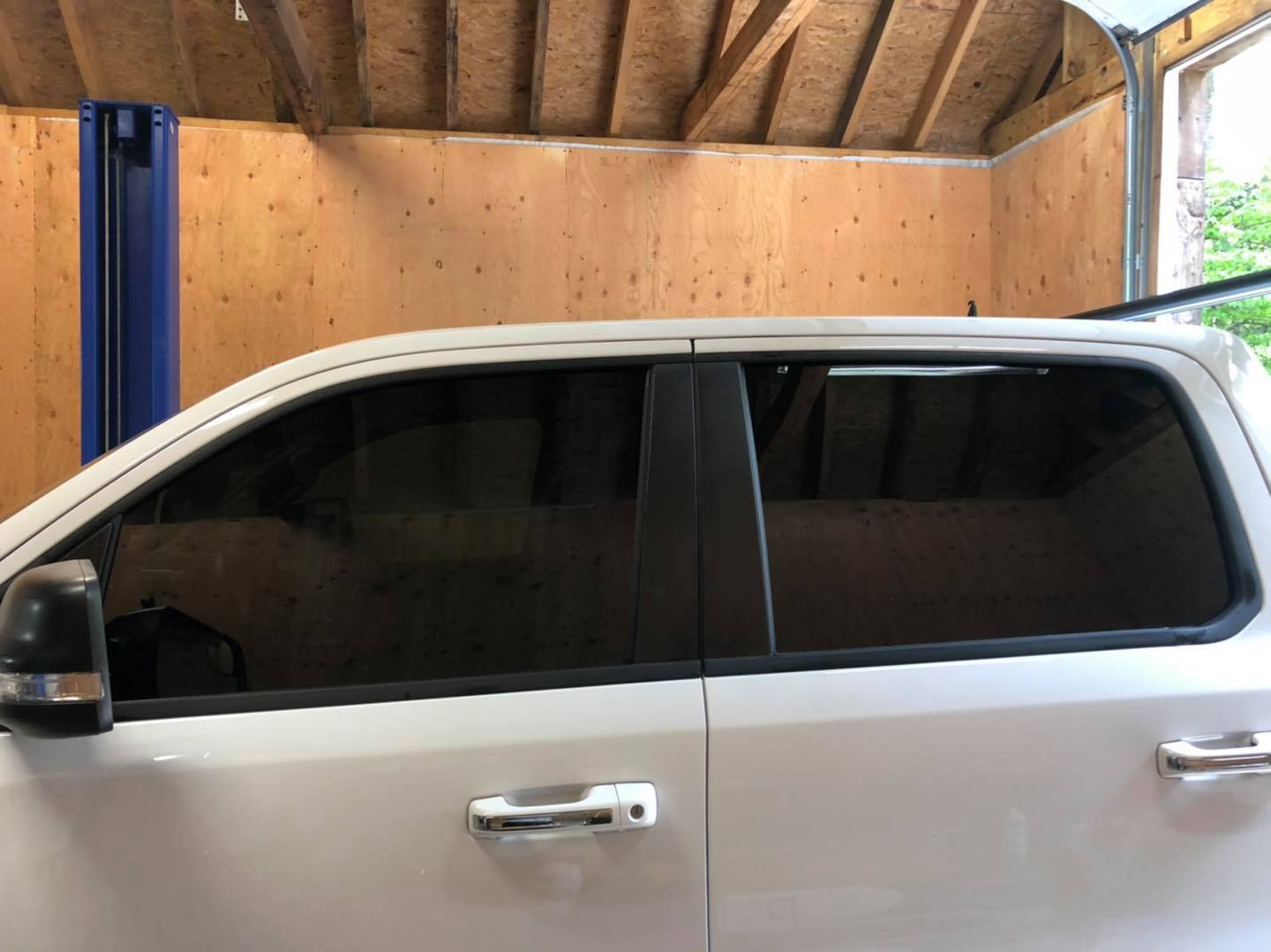 White pickup truck with tinted windows inside a garage.