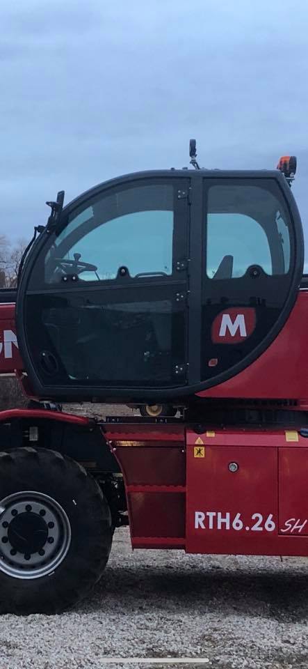 Red Manitou telehandler with glass cab. 