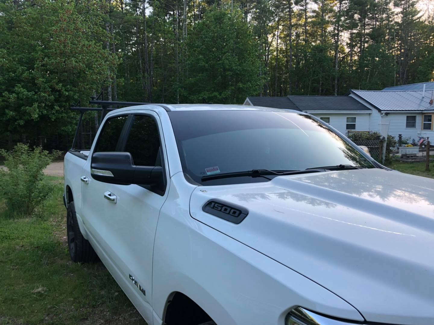 White pickup truck with tinted windows parked outside; trees and house in the background.