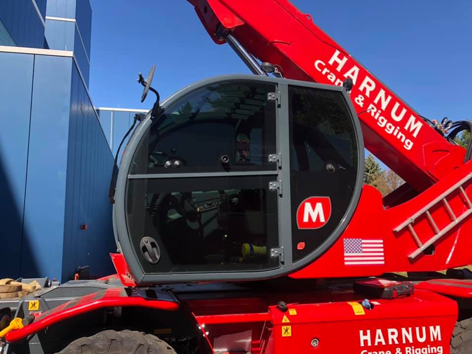 Red telehandler crane cab with Harnum Crane & Rigging logo and American flag.