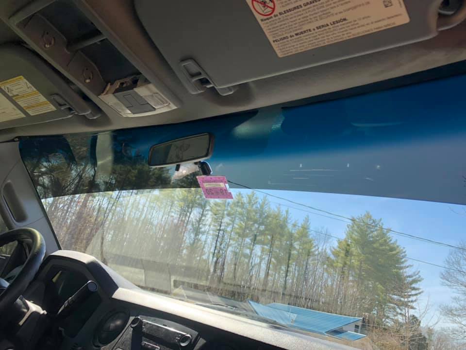 Interior view of a vehicle, looking through the windshieun visors and rearview mirror are visible.