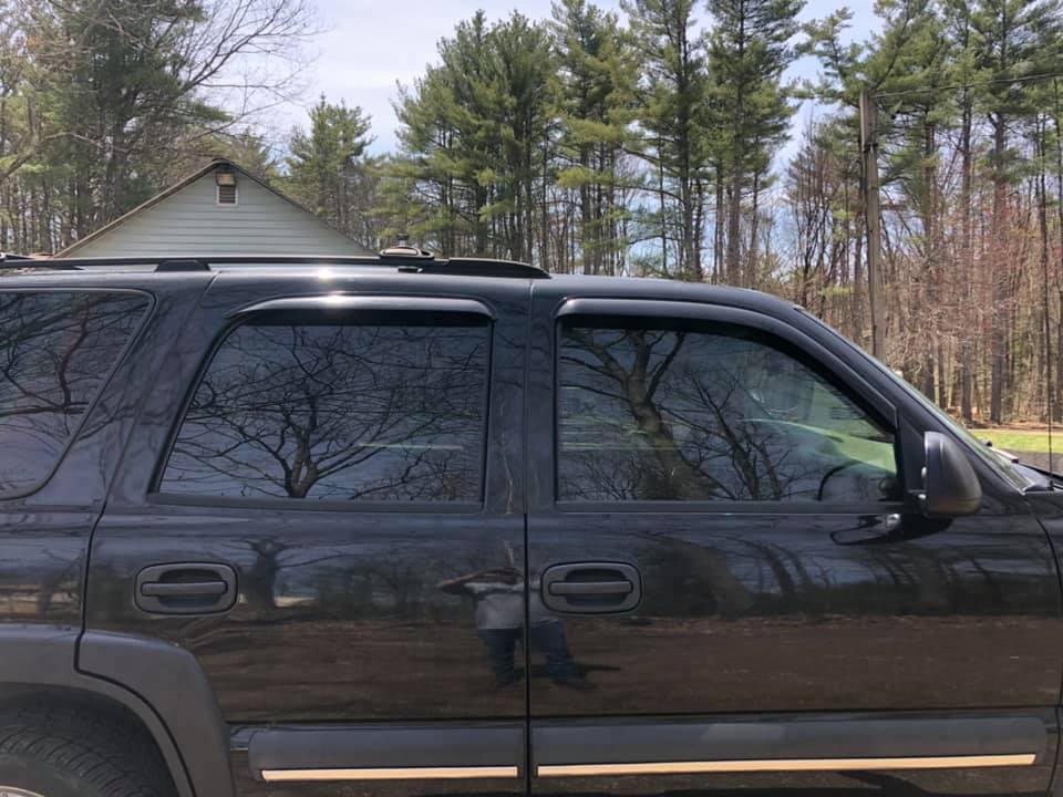 Black SUV with tinted windows parked outside on a sunny day.