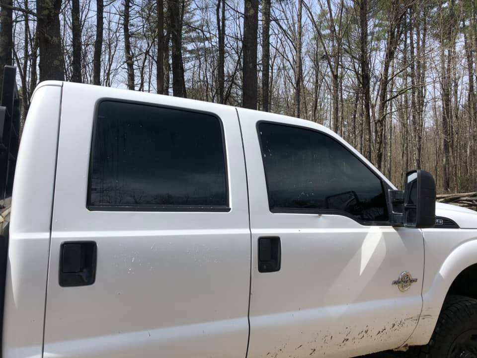 White pickup truck with tinted windows parked in a wooded area.