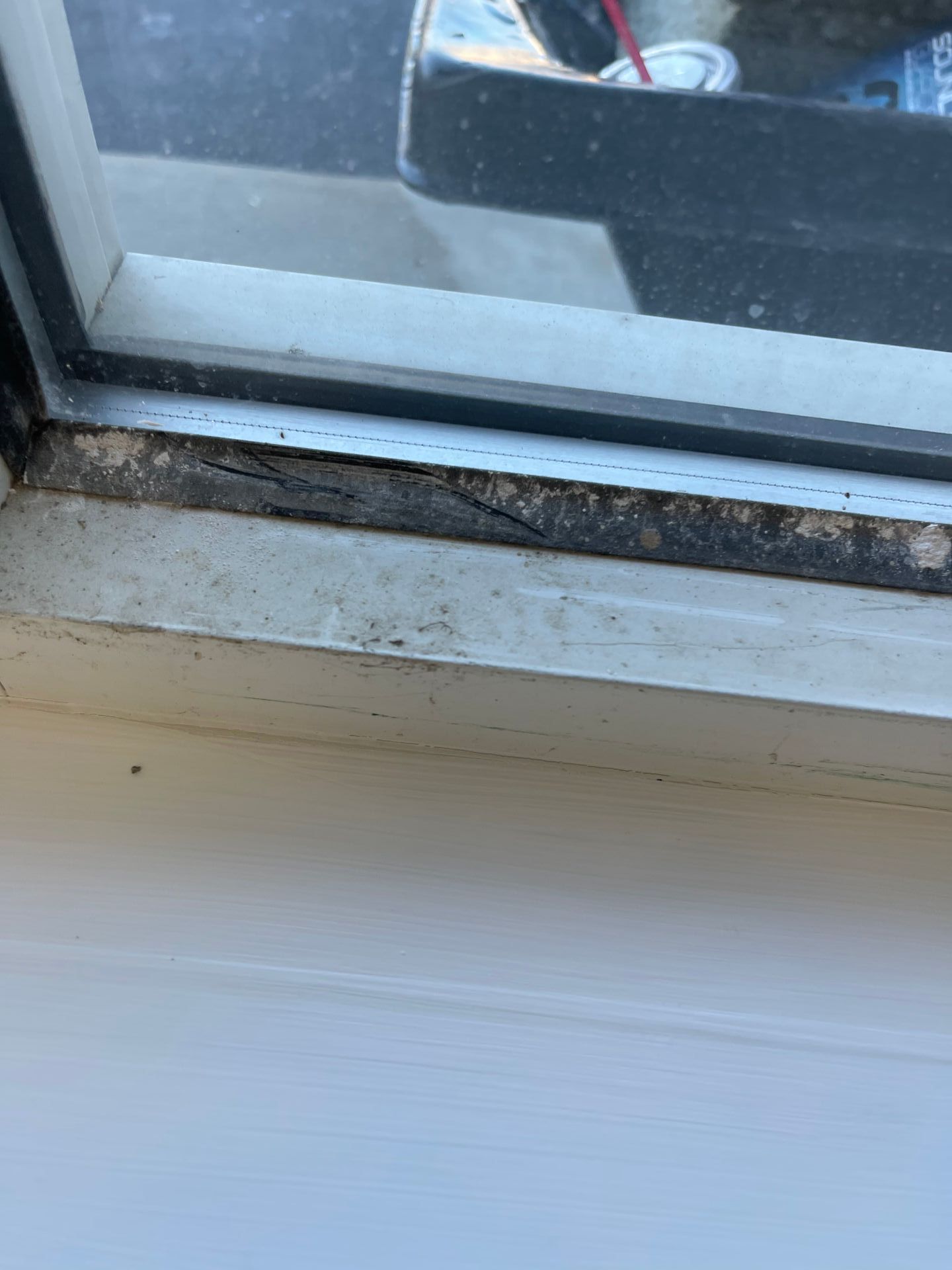 Close-up view of a window frame with signs of mold and wear along the edges.