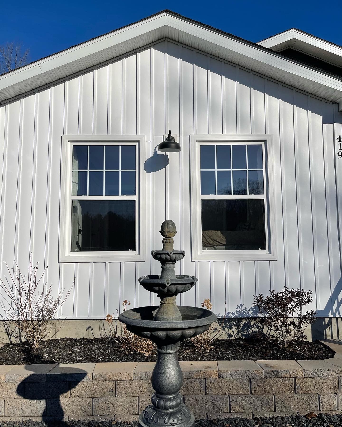 White building with two windows, a fountain in front.