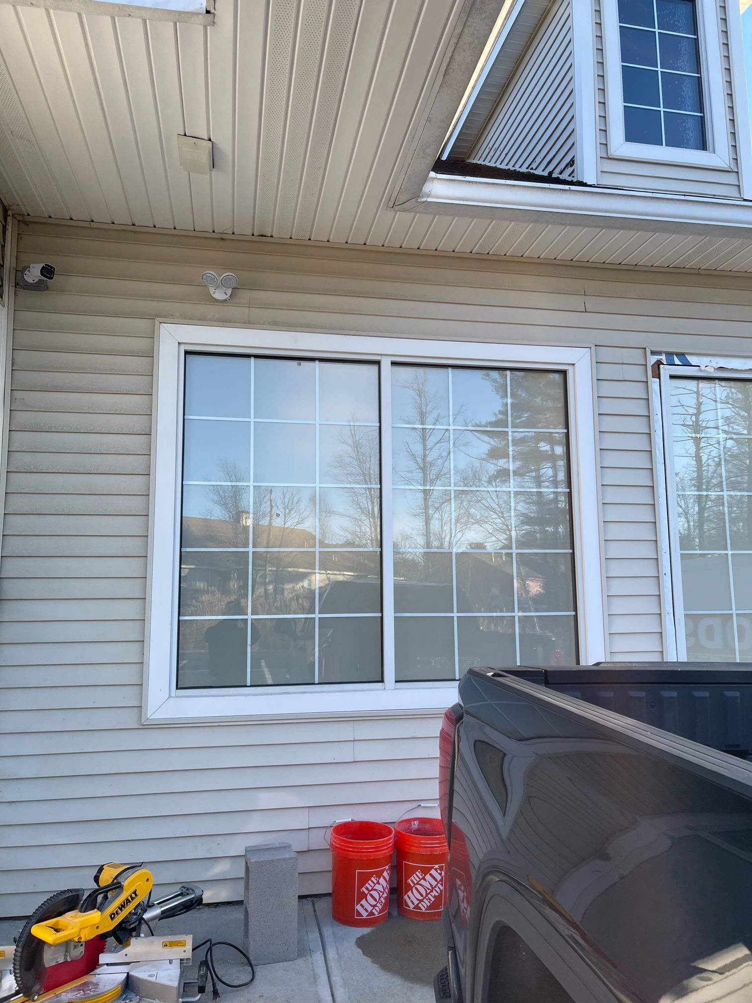 Exterior of a house with a sliding glass window. A truck bed and tools are in front.