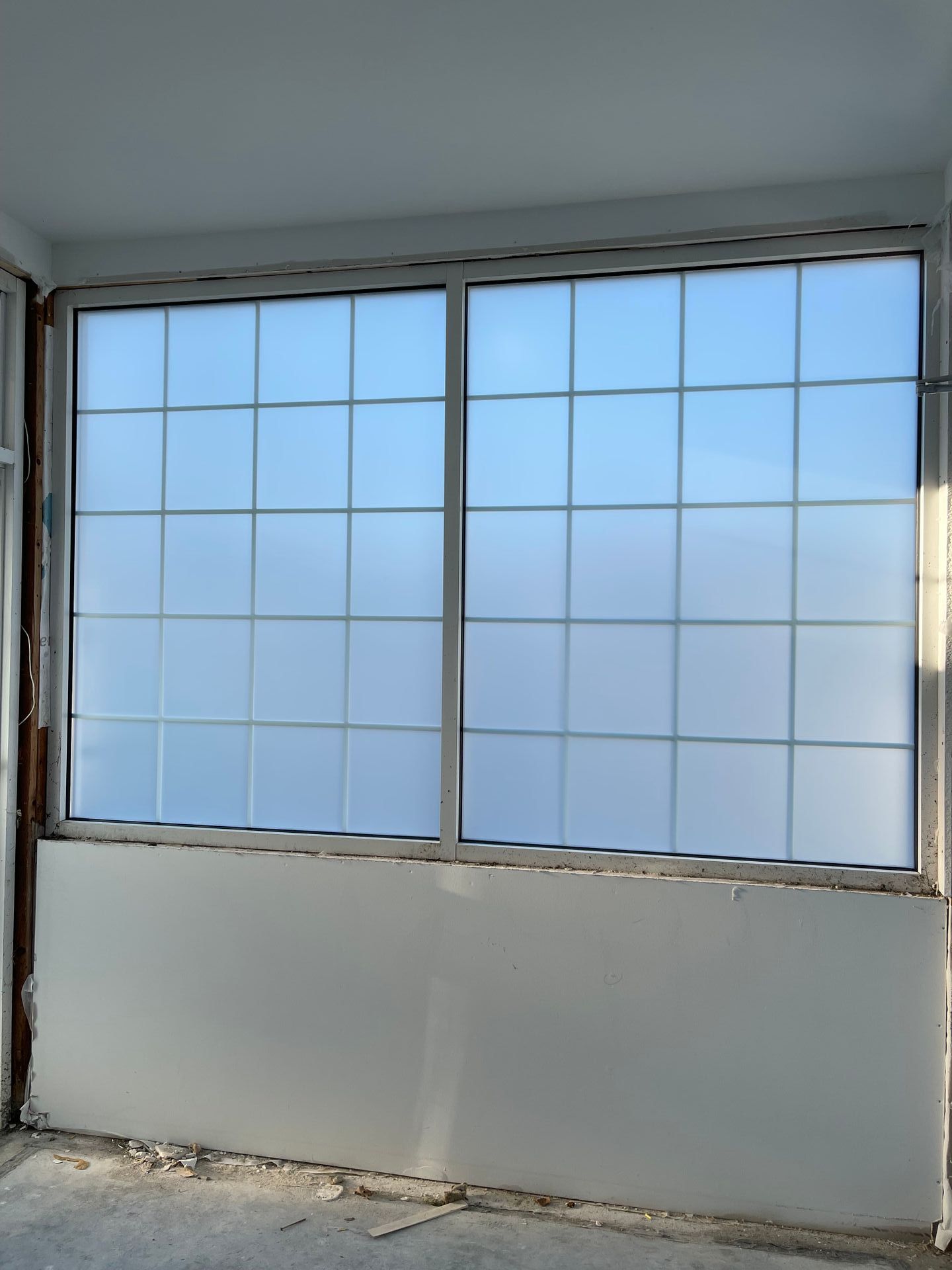 Large window with a grid pattern, frosted glass, and partially constructed wall.