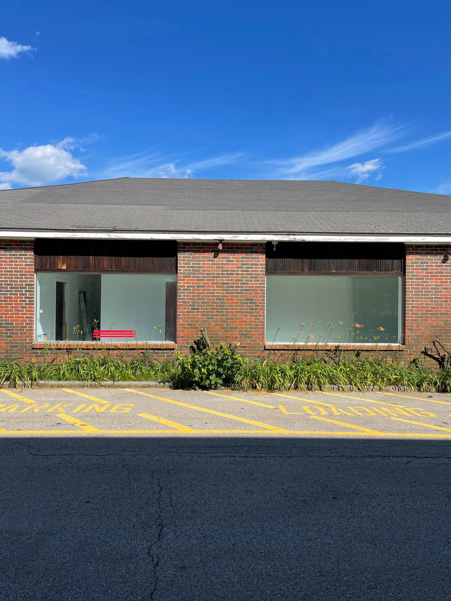 Brick building with two large windows. The windows are empty, and blue sky above.